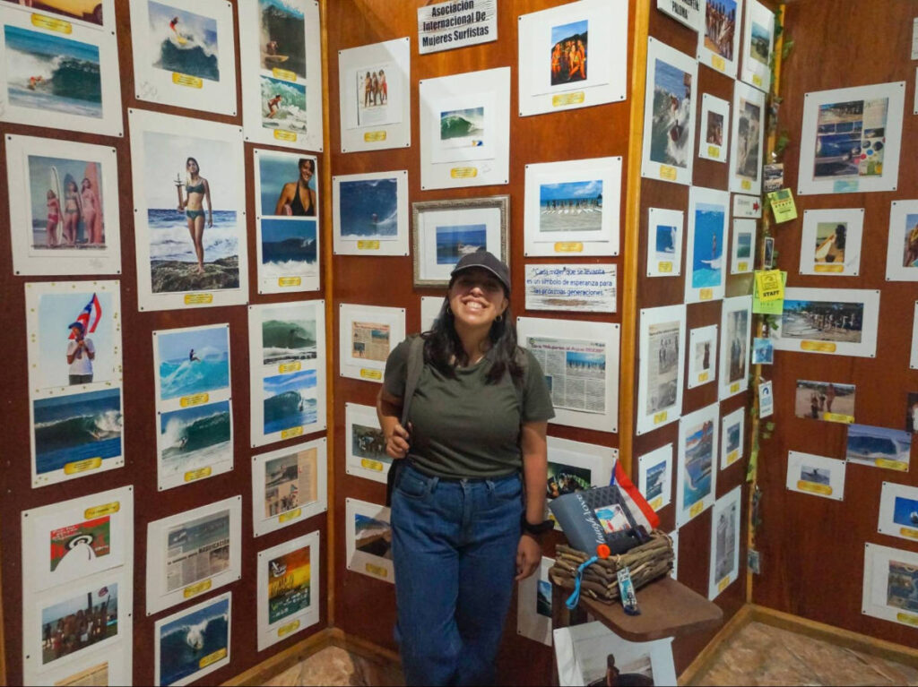 The author Vanessa Ramos, standing in front of the wall gallery at Galería del Surfing