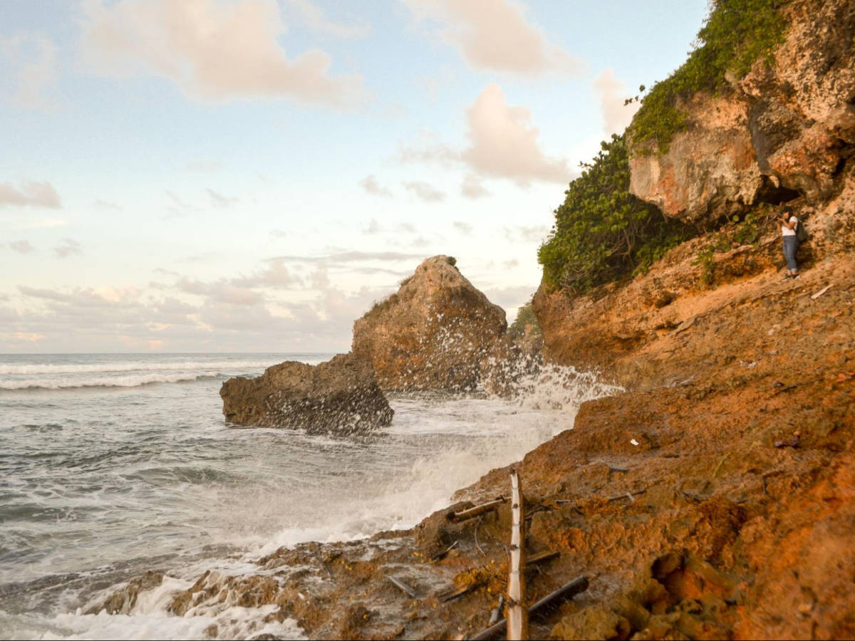 The author Vanessa Ramos, hiking on the rock formations with huge waves crashing on the rocks in Survival Beach