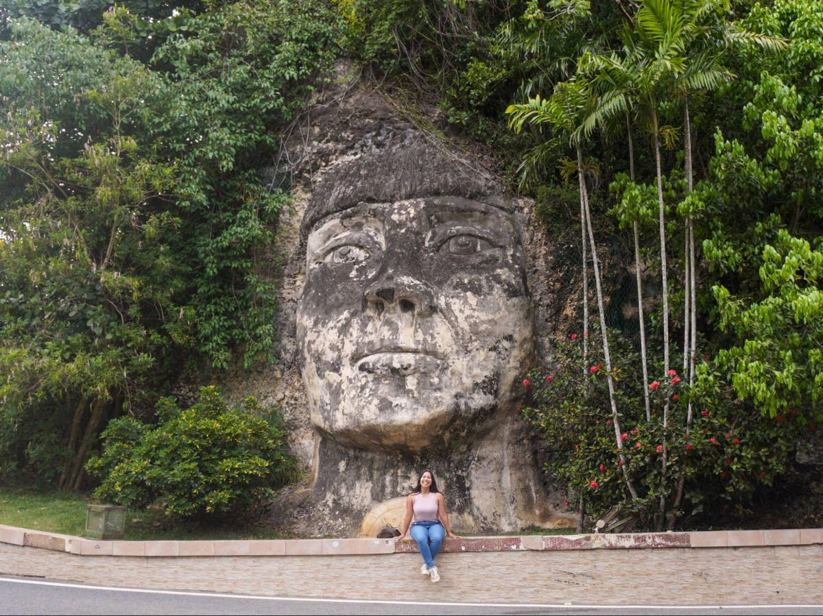 The author Vanessa Ramos, posing for a photo in front of the Taino Indian face carved in a rock
