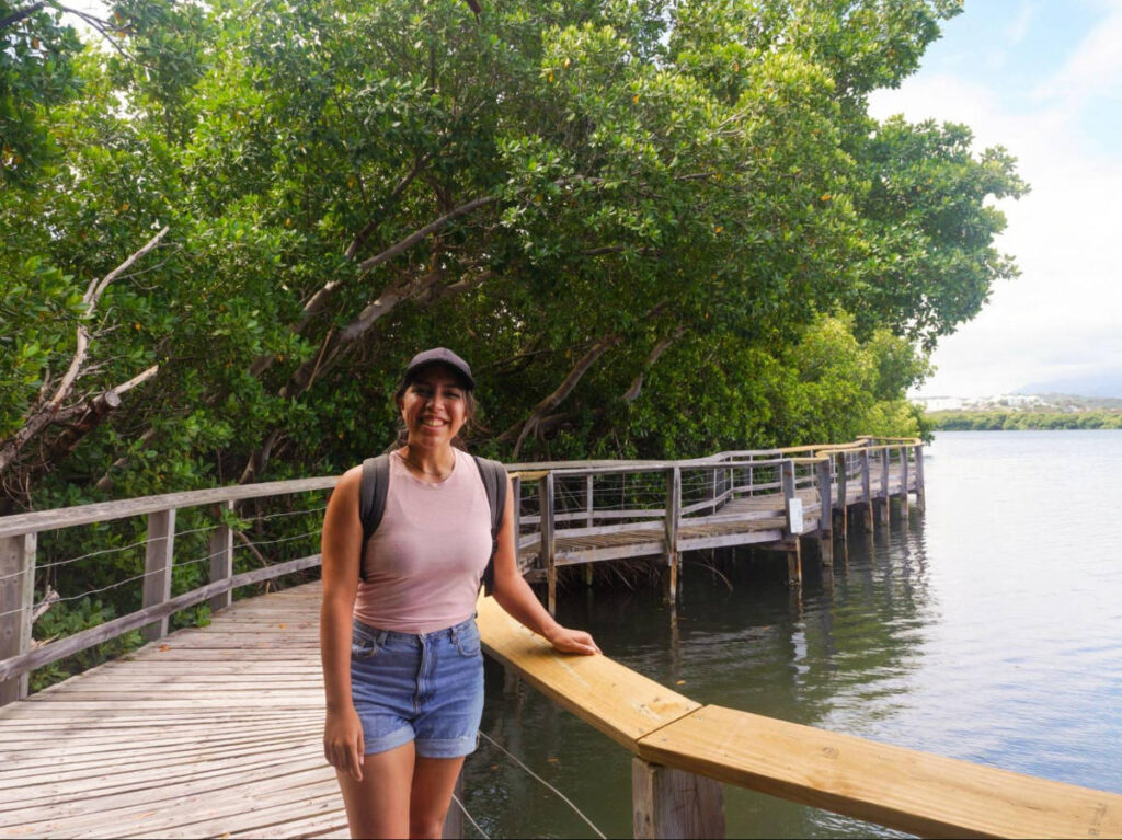 The author Vanessa Ramos, smiling for a photo while on a boardwalk next to Laguna Grande