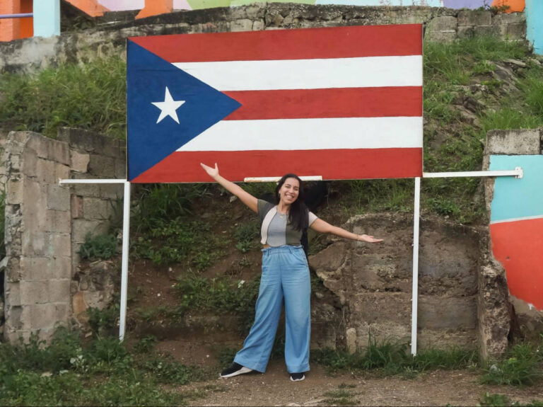 The author Vanessa Ramos, standing in front of the flag of Puerto Rico
