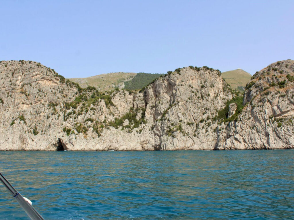 A boat sailing near a rocky cliff
