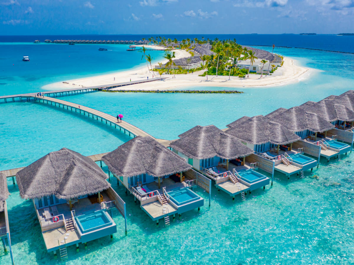 Aerial view of Maldives island, luxury water villas resort and wooden pier