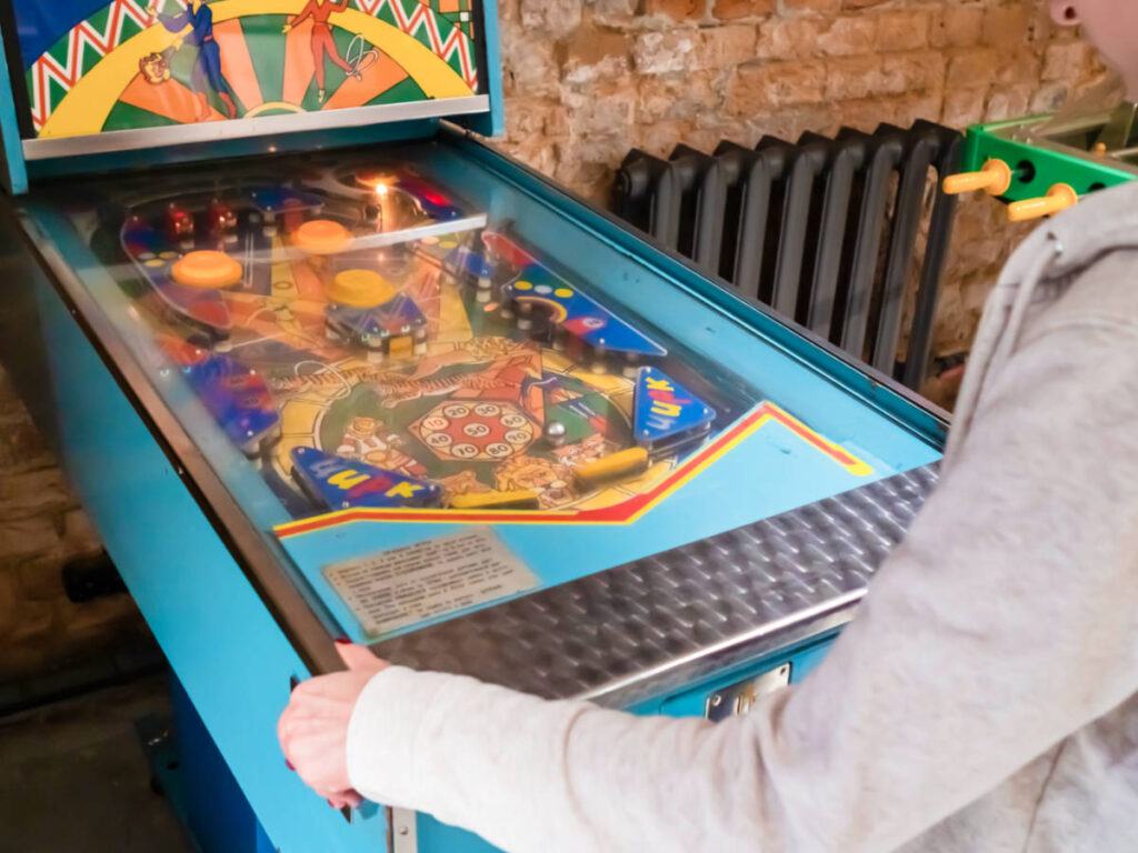 A woman playing the vintage pinball machine