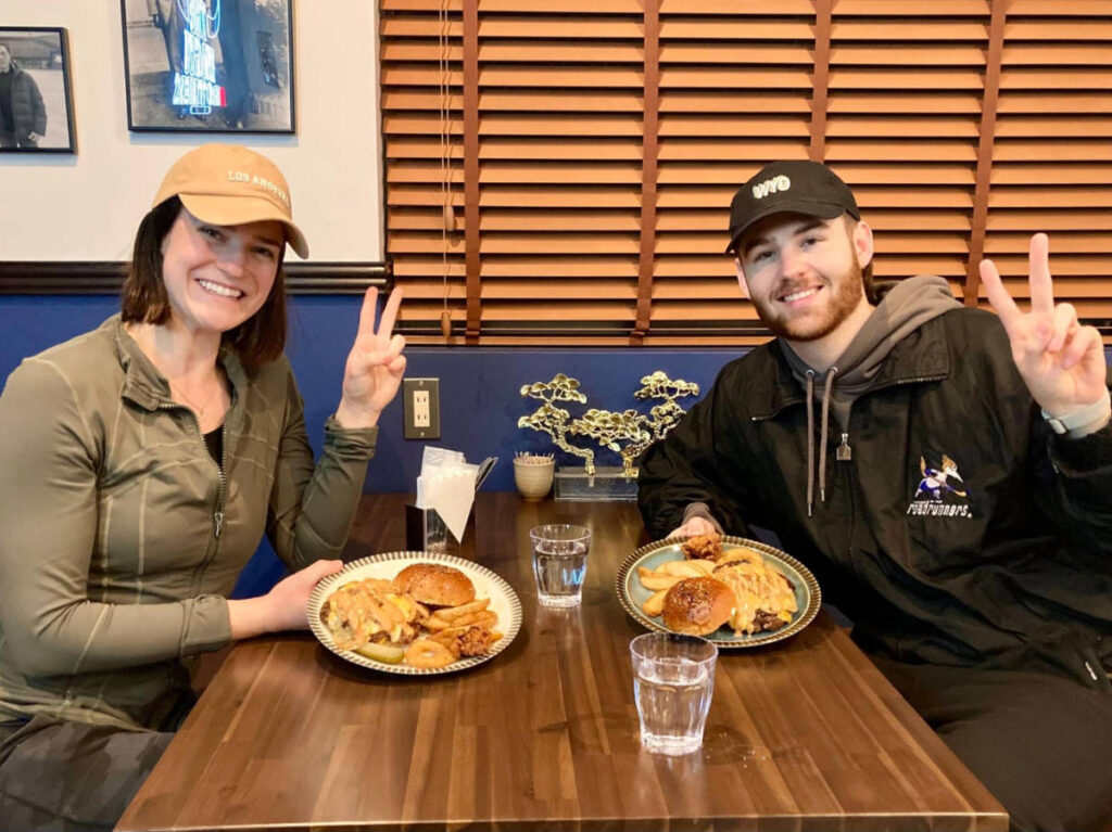 The author, Betty Hurd with her boyfriend posing for a photo holding their Wagyu burgers
