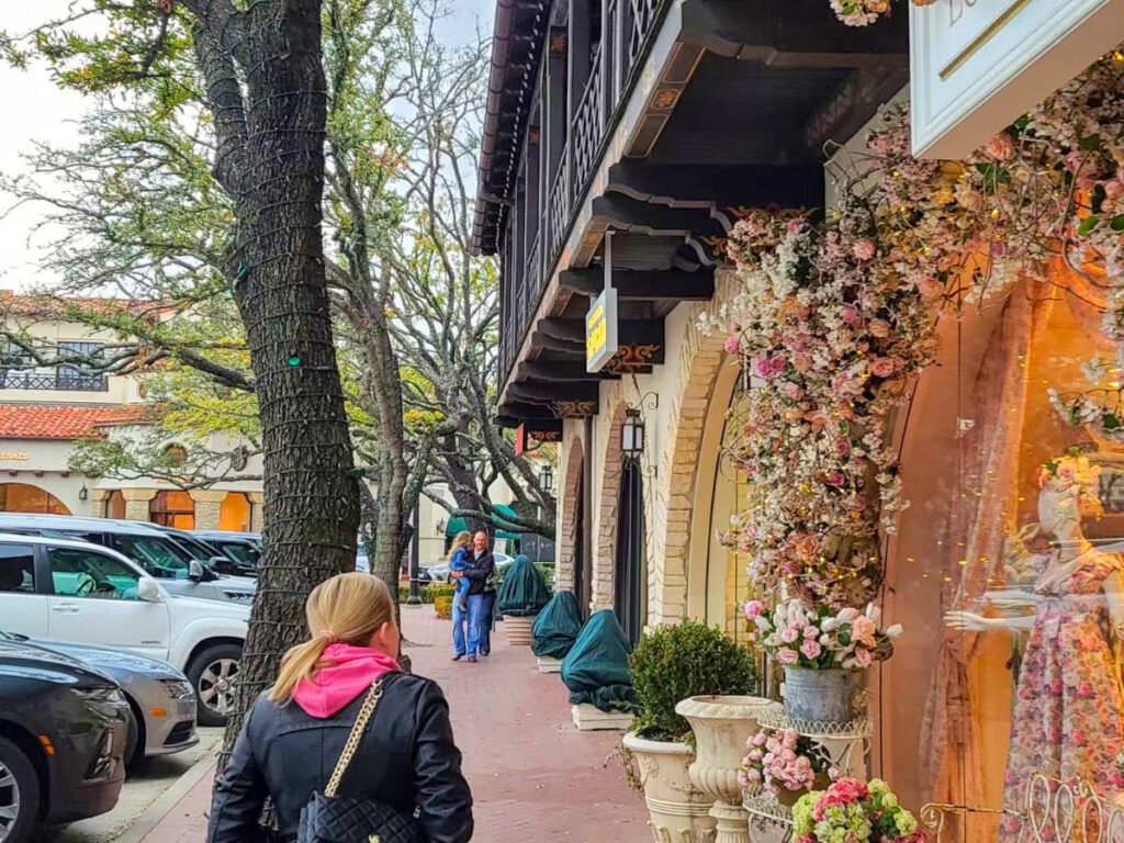 Author Sarah Heath strolling along the sidewalk at Highland Park Village, passing by a store