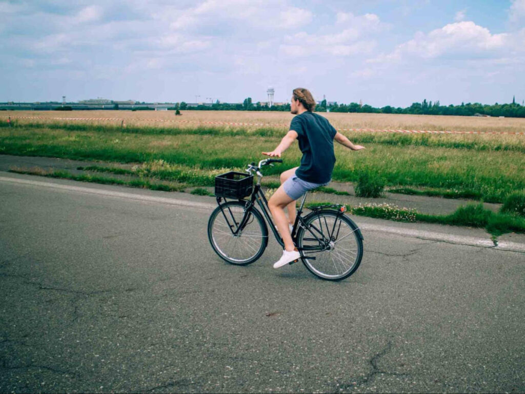 The author's boyfriend biking while pretending to be a plane along Tempelhofer Feld