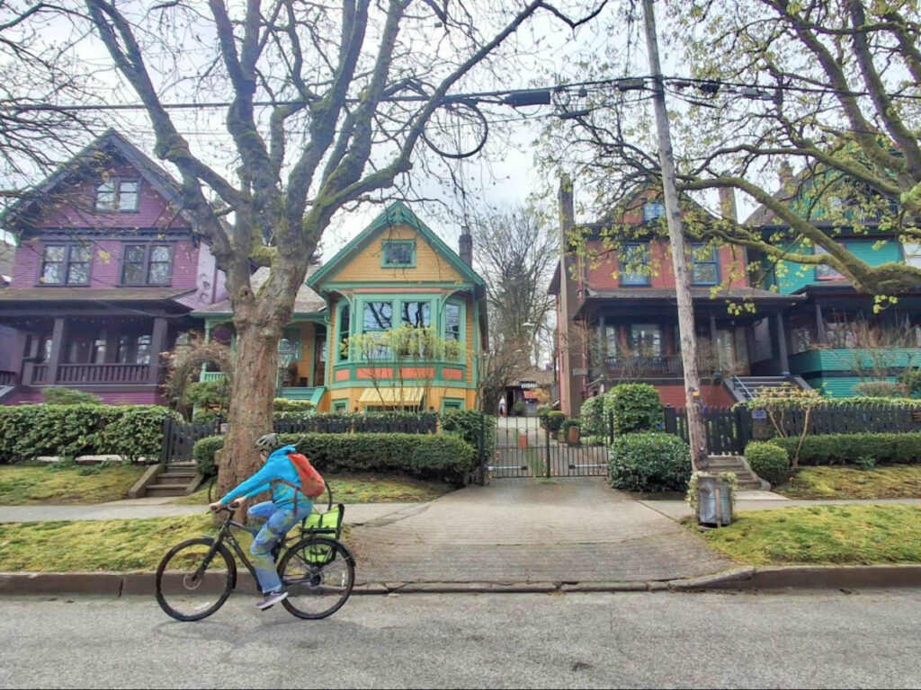 A woman cycling along the “Painted Ladies” heritage homes in West 10th