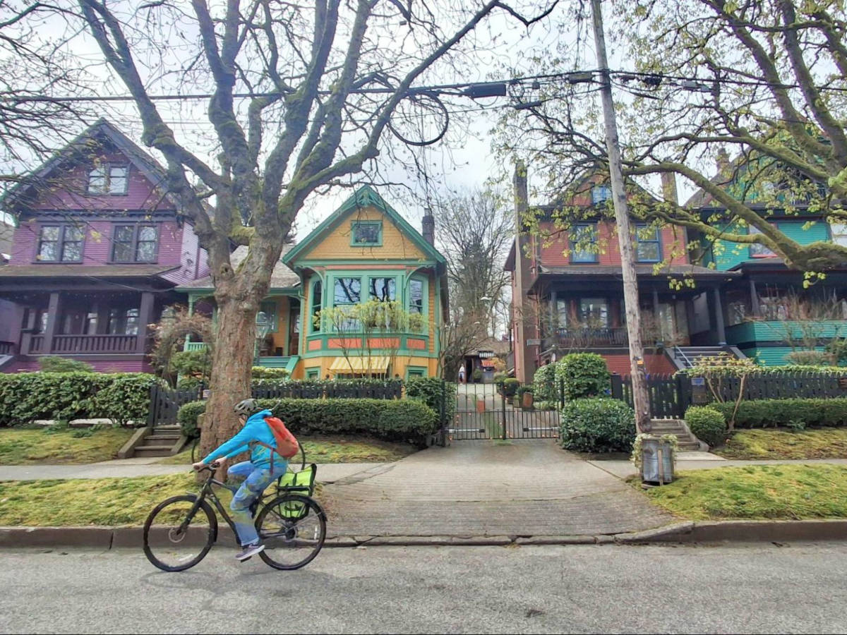 A woman cycling along the “Painted Ladies” heritage homes in West 10th