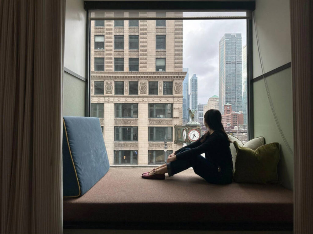 The author, Lea Rose Allbaugh admiring the view from her nook window on her room at L7 Chicago by Lotte
