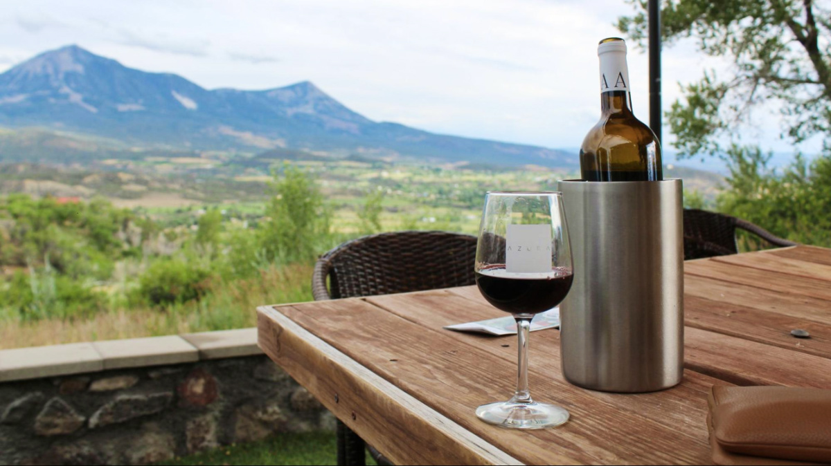 A wine bottle and a glass of wine on the patio at Azura Cellars and Gallery