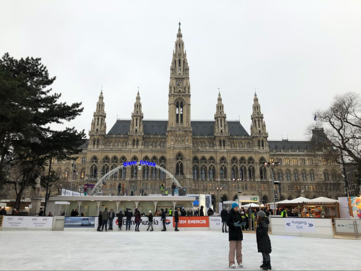 Ice skaters at an outdoor rink in front of Vienna City Hall during winter