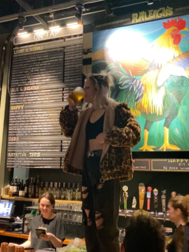 A woman drinking a glass of beer on top of the bar