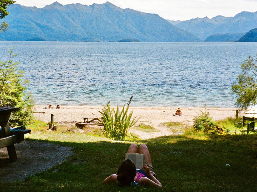 A woman reading a book near the lake