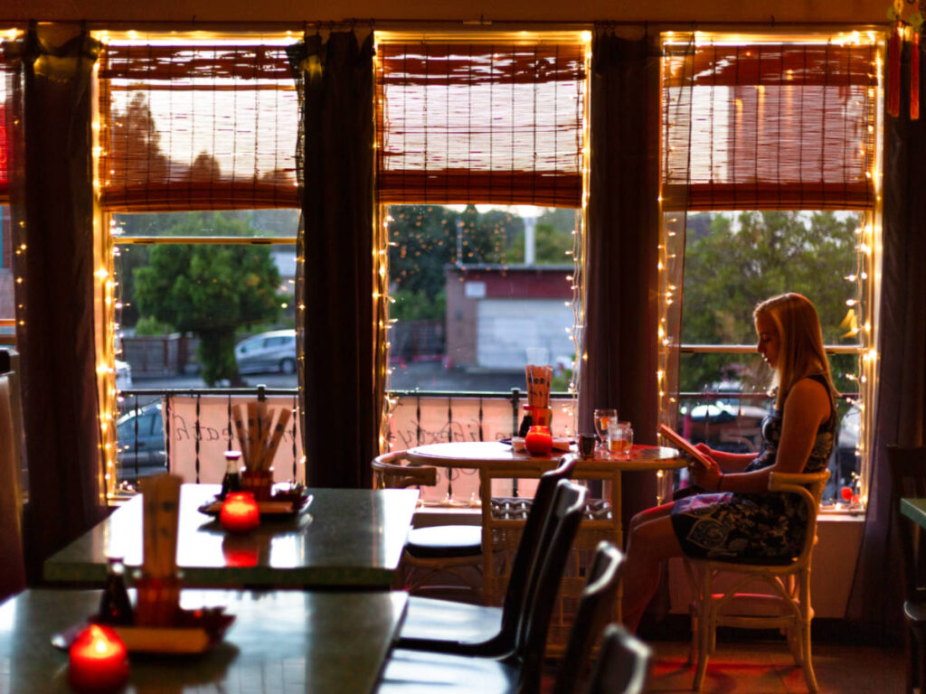 A woman reading inside the cozy interior of Mee Heng Low Noodle House