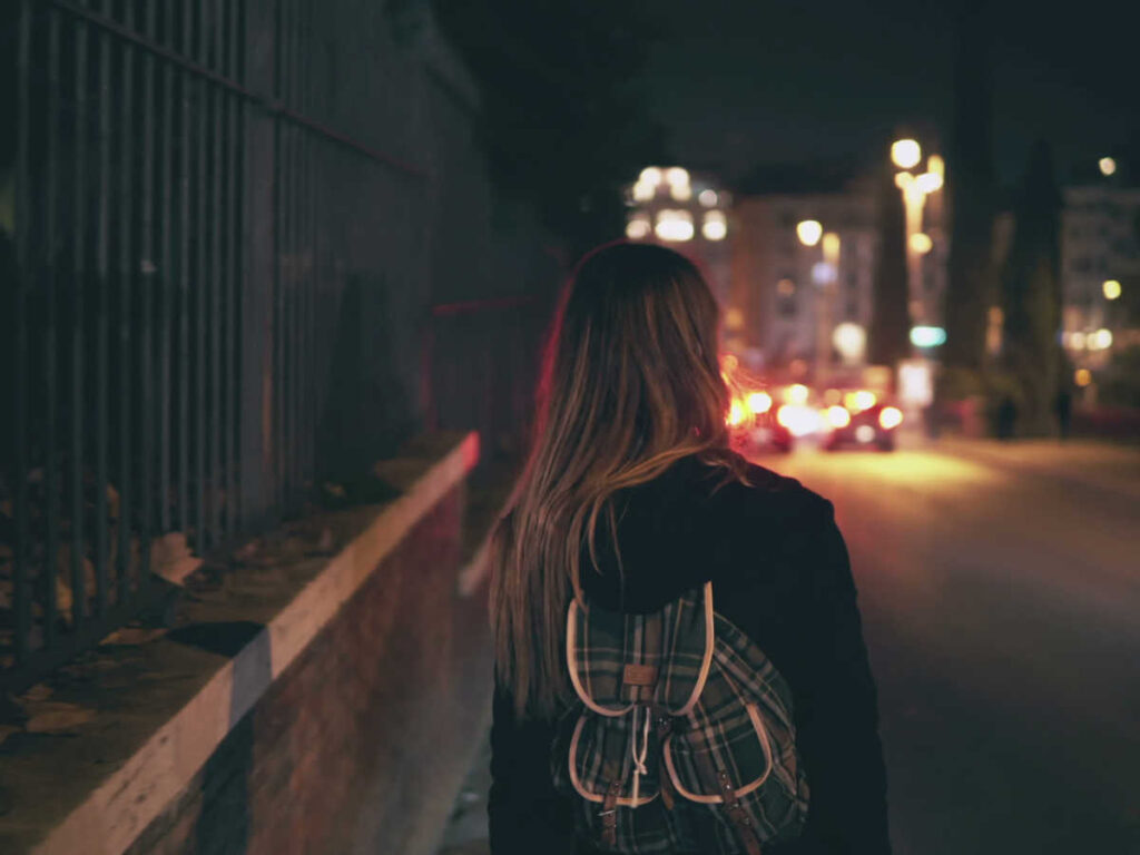 A woman walking along a dark street at night