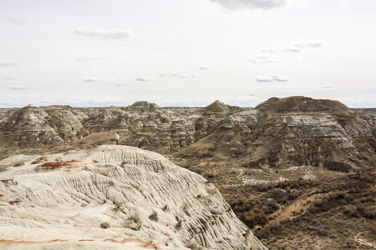 A woman stands atop carved sandstone rock in Dinosaur Provincial Park