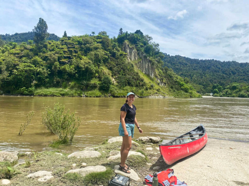 A woman standing near the canoe at Whanganui River