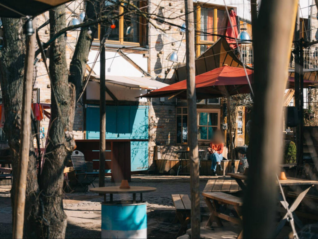A woman sitting on the bench seen behind the trees in Holzmarkt 25
