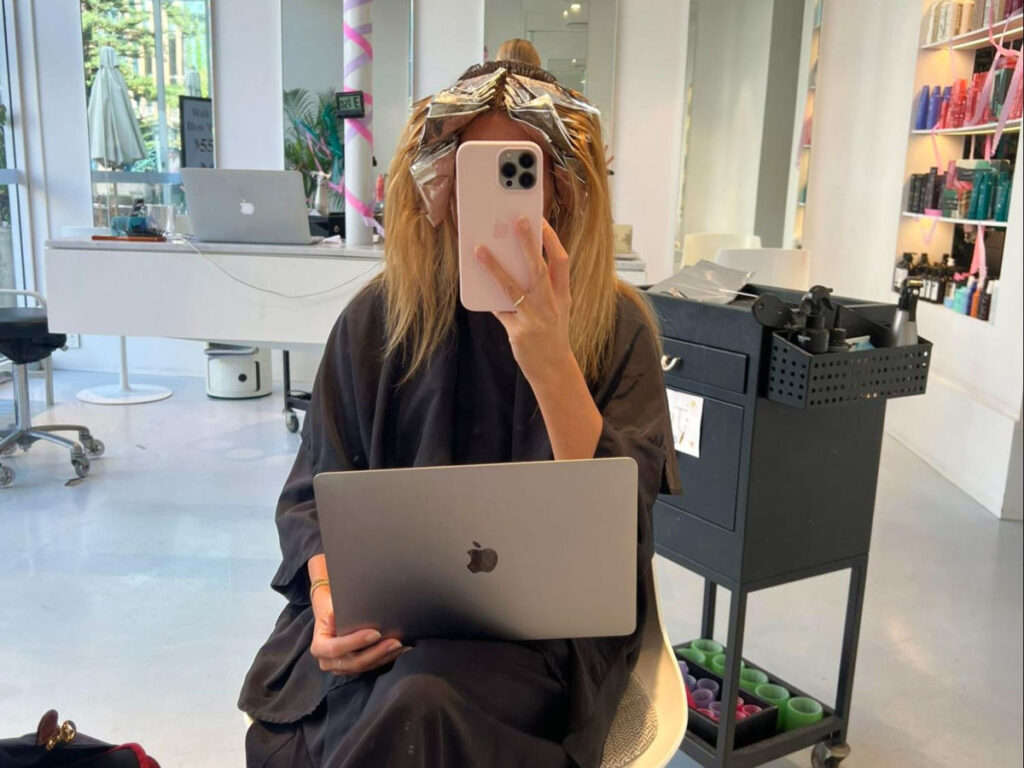 A woman holding her laptop and working on her day off at the salon